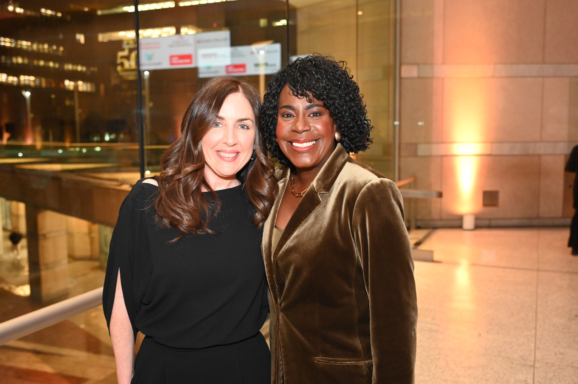 Two women smiling for a photo inside Philadelphia City Hall, standing together in the building’s illuminated lobby.