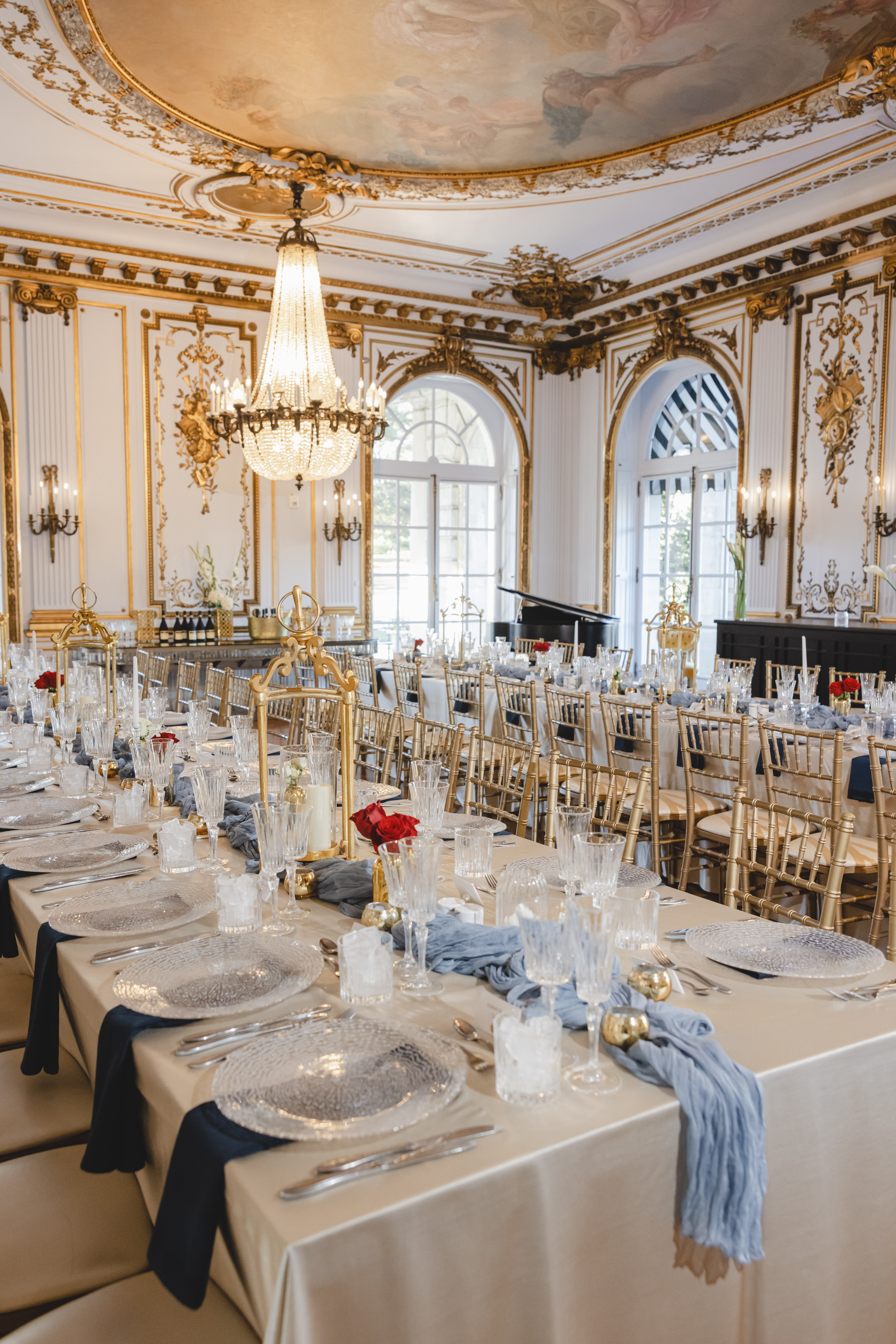 mansion room lined with banquet tables and large chandelier