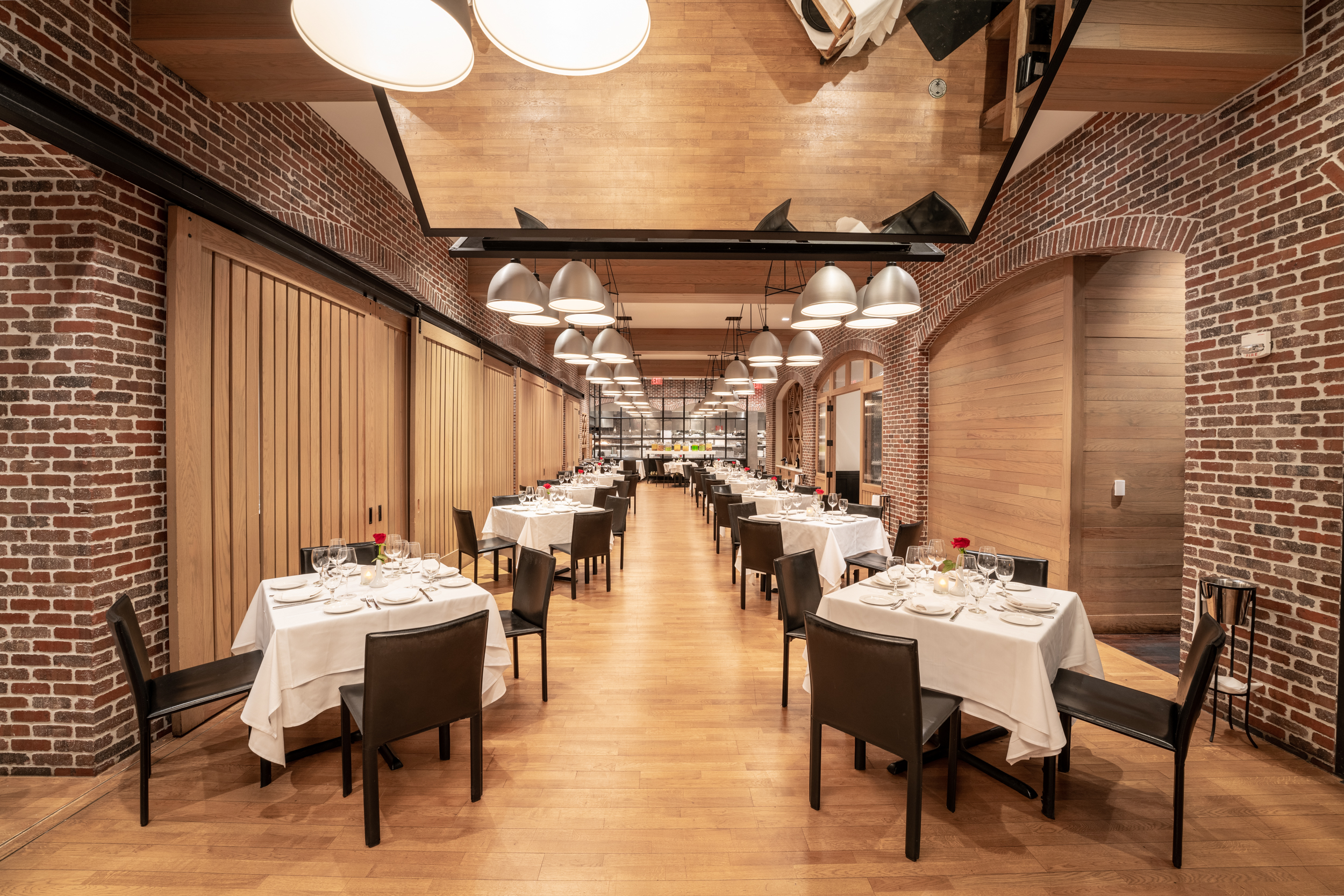 long room lined with small dining tables and brick walls
