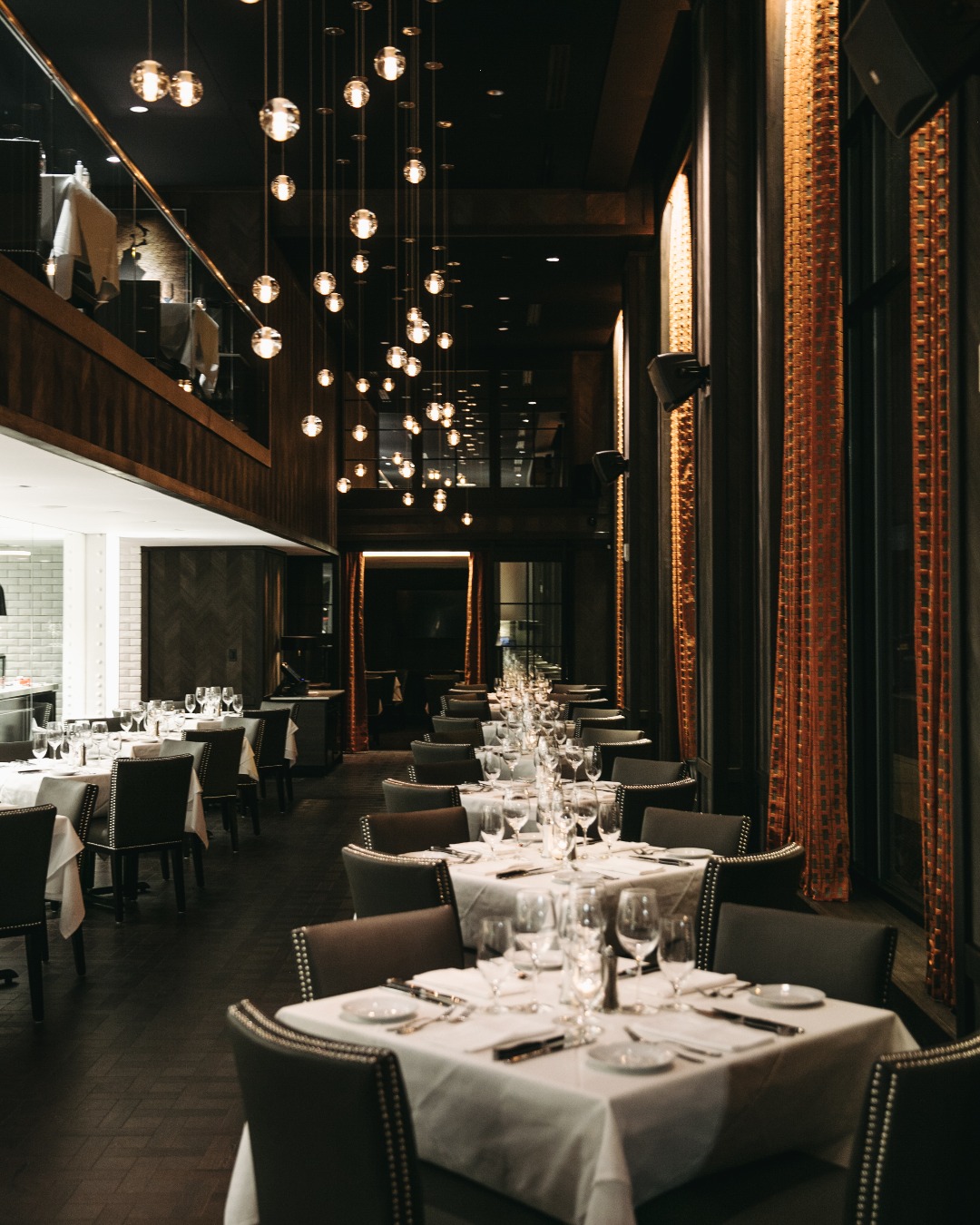 Dimly lit dining room with dining tables and light bulbs lining ceiling